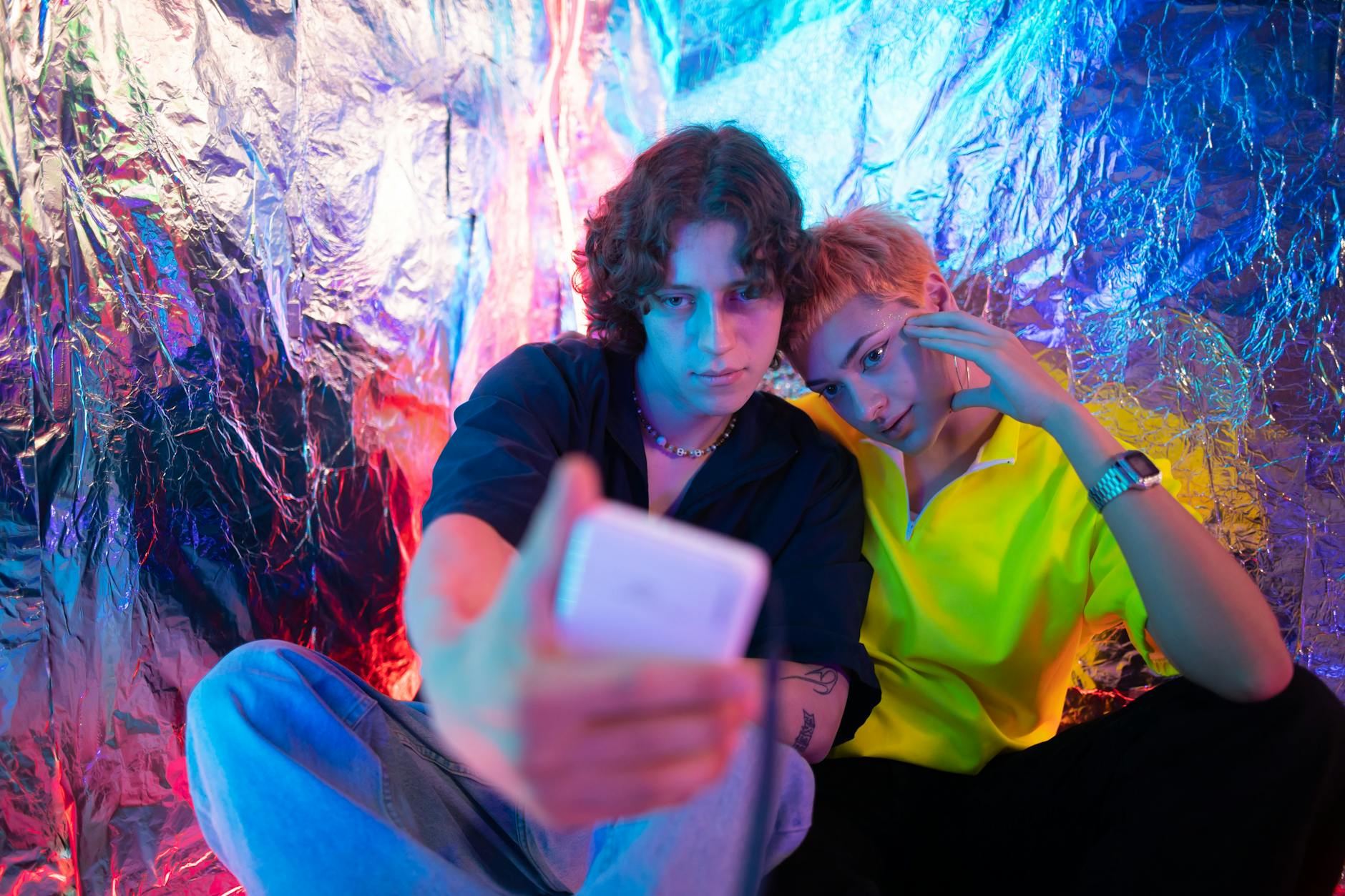 カフェでスマートフォンを見ながら楽しく会話する若いカップル